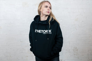 Blonde woman wearing black hoodie with 'Rhetorik' written on chest