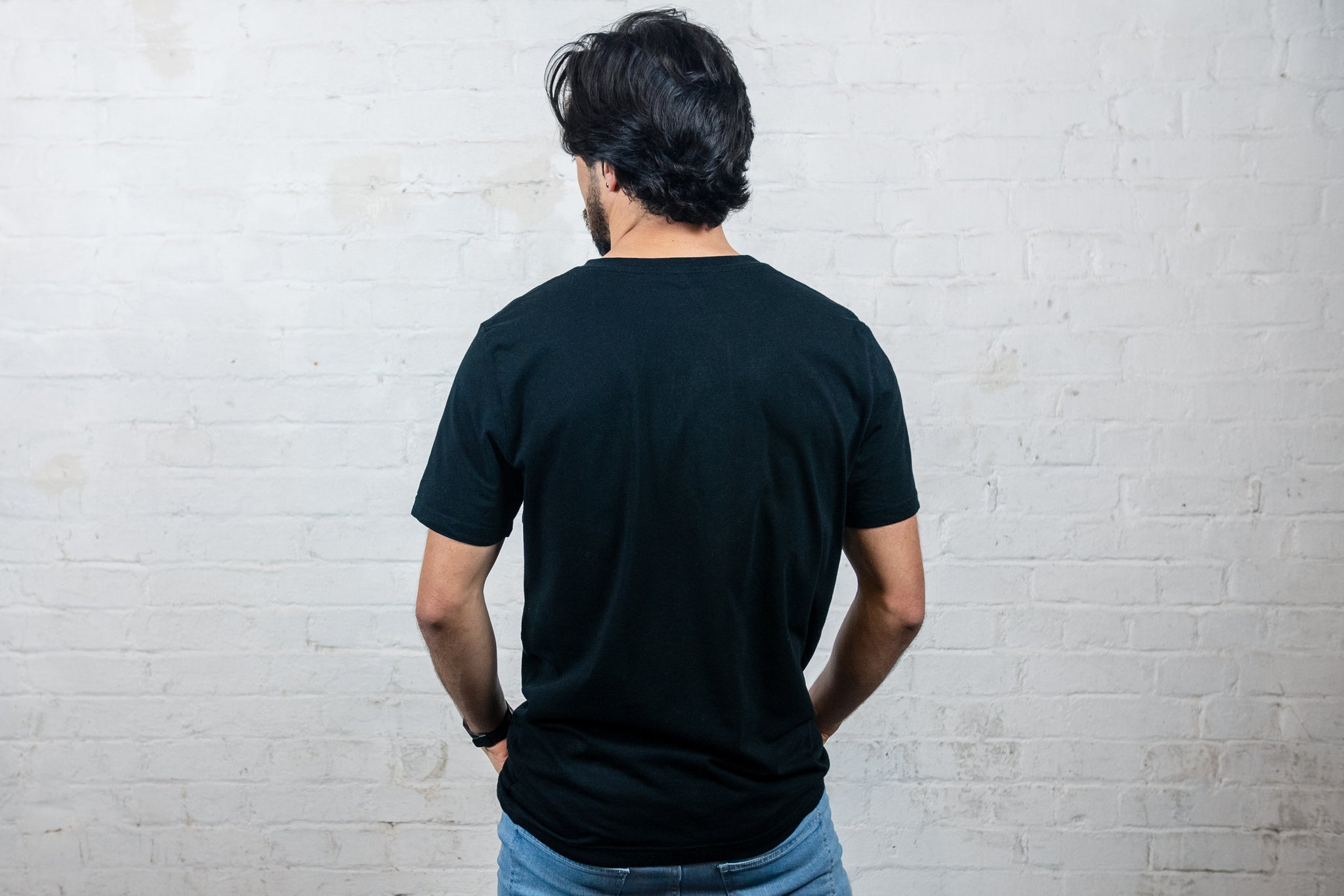 Back of Rhetorik organic clothing logo T-shirt, blank, worn by male model in studio. 