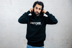 Male model wearing black hoodie holding edges of hood