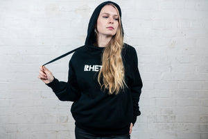 Female model wearing black Rhetorik hoodie pulling adjustment cord