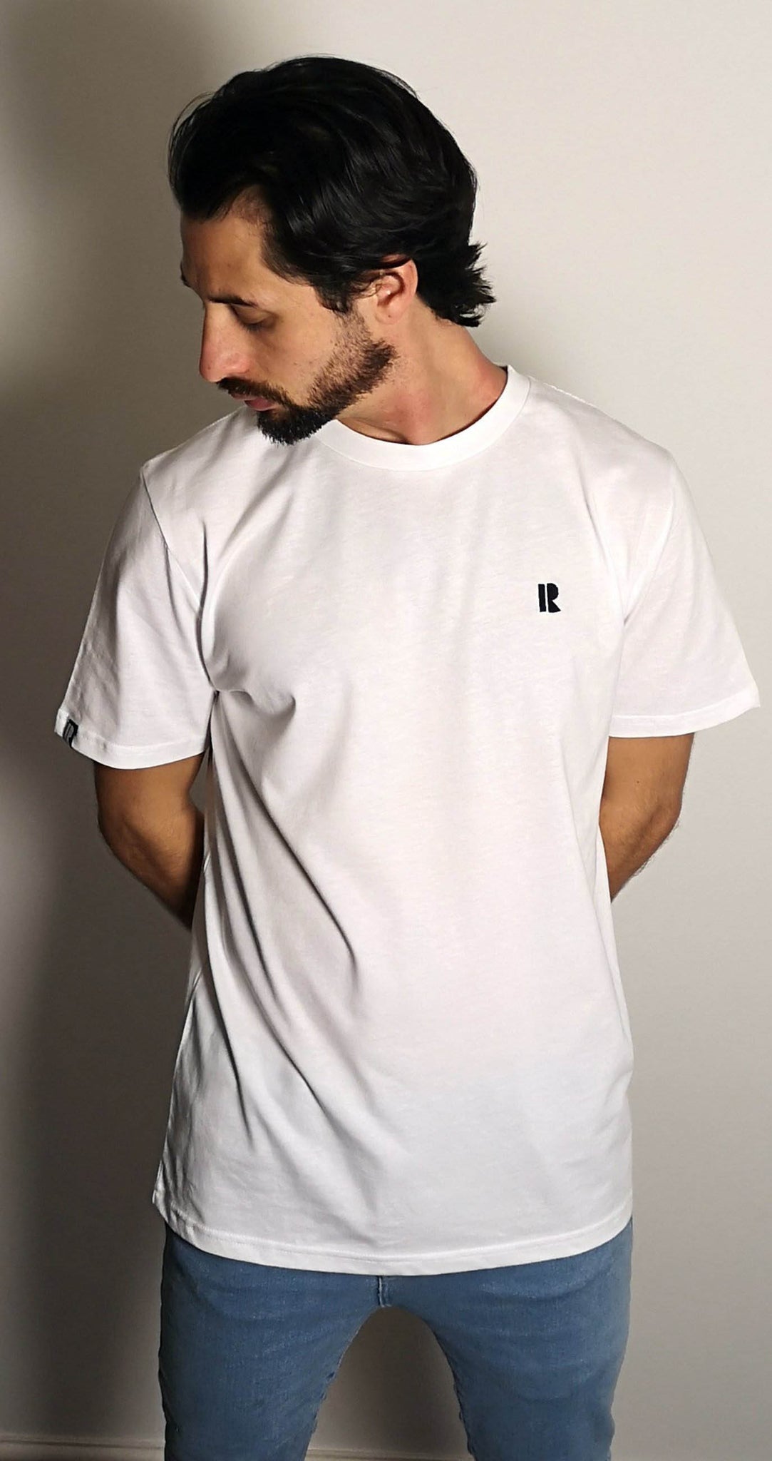 Man model wearing white Rhetorik T-shirt with mini-R embroidered